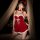 A woman poses in a festive red velvet sleep dress with white fur trim, featuring lace-up detailing and bow accents, perfect f...