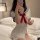 Woman in xintao sexy nurse costume set, a sweet & seductive college-style uniform with red bow, posing on bed.