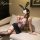 Woman in purple floral lingerie set with pencil skirt, bunny ears, and garter stockings on couch.