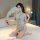 Woman modeling light blue sheer mesh lingerie set with cutouts, holding white feather fan on bed.