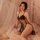 Woman wearing yue die sexy lace sleepwear set with cut-out cami and matching robe, sitting on bed with soft lighting.