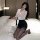 A woman poses elegantly on a bed wearing a stylish yujie-style secretary outfit, featuring a sheer white blouse paired with a...